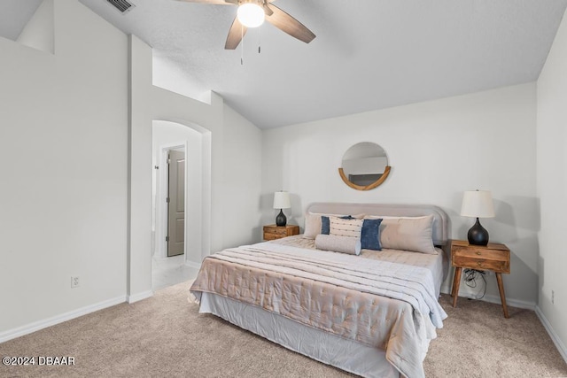 carpeted bedroom featuring baseboards, lofted ceiling, arched walkways, and a ceiling fan