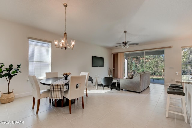 tiled dining area with ceiling fan with notable chandelier and a healthy amount of sunlight