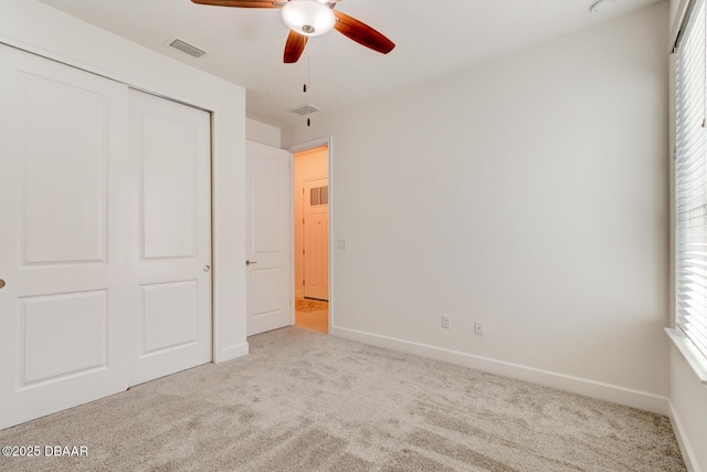 unfurnished bedroom with light colored carpet, a closet, and ceiling fan