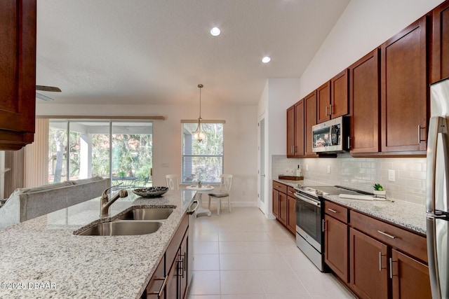 kitchen with light stone counters, sink, decorative light fixtures, and appliances with stainless steel finishes