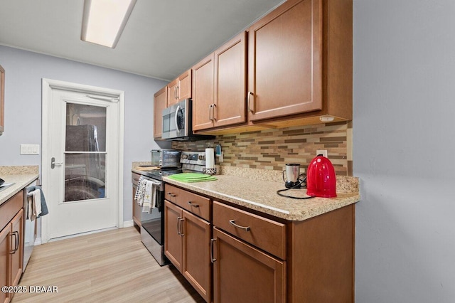 kitchen featuring appliances with stainless steel finishes, light hardwood / wood-style floors, and backsplash