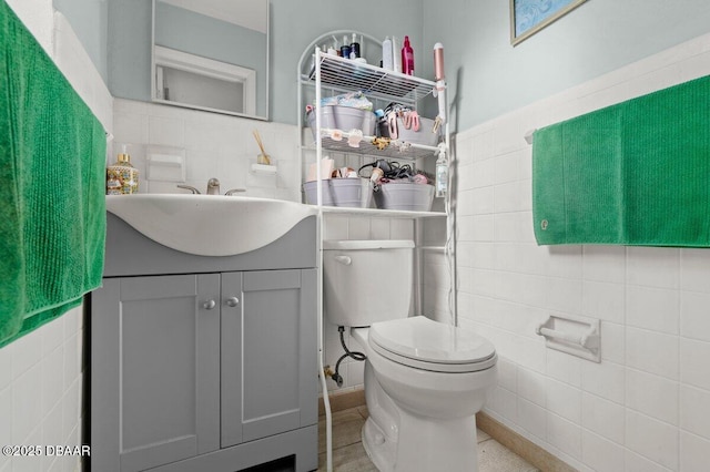 bathroom with toilet, tile patterned floors, vanity, tile walls, and decorative backsplash