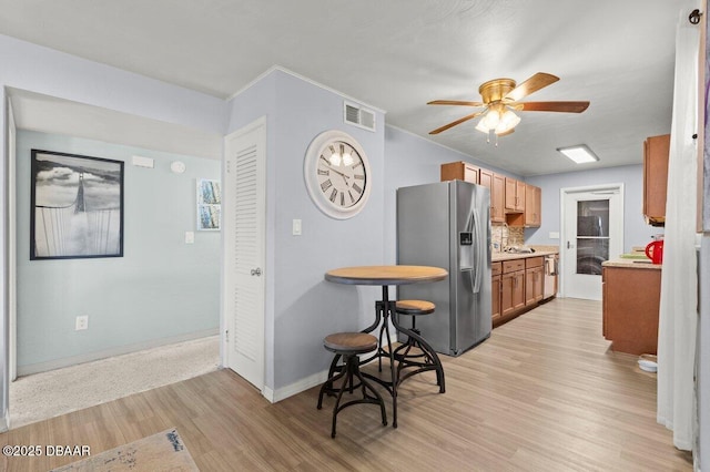 kitchen featuring ceiling fan, stainless steel fridge with ice dispenser, light hardwood / wood-style flooring, and tasteful backsplash