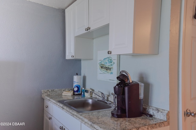 kitchen with white cabinetry, sink, and a textured ceiling