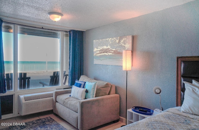 tiled bedroom featuring a wall unit AC and a textured ceiling