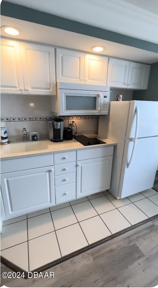2700 N Atlantic Ave Unit 1021, Daytona Beach, FL 32118 - kitchen featuring white appliances, a sink, white cabinets, light countertops, and light wood-style floors