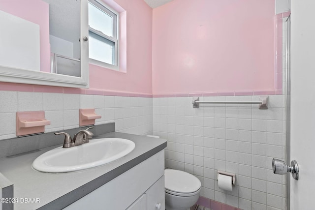 bathroom featuring a textured ceiling, vanity, toilet, and tile walls