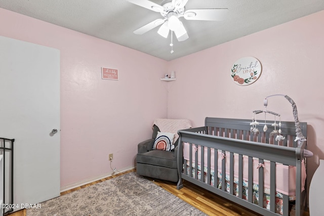 bedroom featuring ceiling fan, wood-type flooring, and a crib