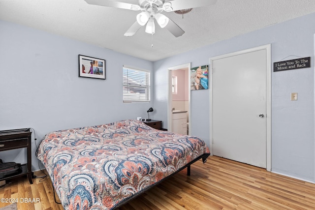 bedroom featuring ceiling fan, light wood-type flooring, a textured ceiling, and ensuite bath