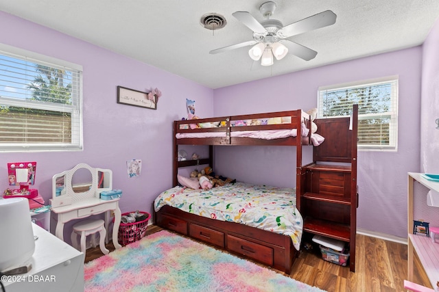 bedroom with a textured ceiling, light wood-type flooring, and ceiling fan