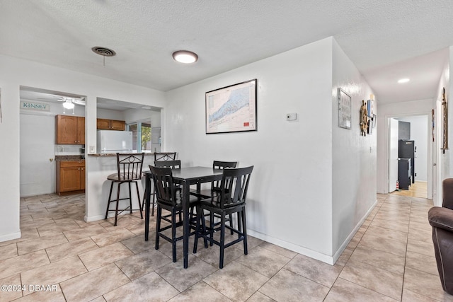 dining space with ceiling fan, light tile patterned floors, and a textured ceiling