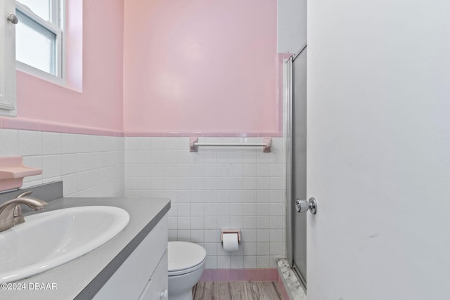 bathroom featuring walk in shower, vanity, hardwood / wood-style flooring, tile walls, and toilet