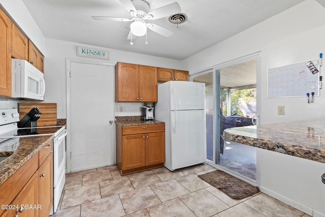 kitchen with ceiling fan, dark stone countertops, white appliances, and a textured ceiling