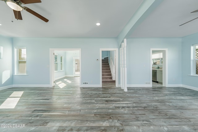 unfurnished living room with recessed lighting, light wood-style flooring, ceiling fan, baseboards, and stairs