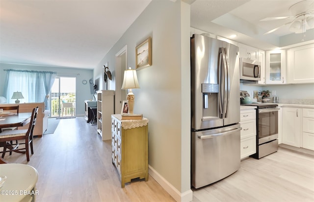 kitchen featuring stainless steel appliances, light countertops, white cabinetry, and light wood finished floors