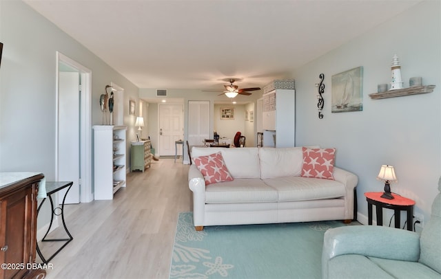 living room with visible vents, ceiling fan, and light wood-style flooring