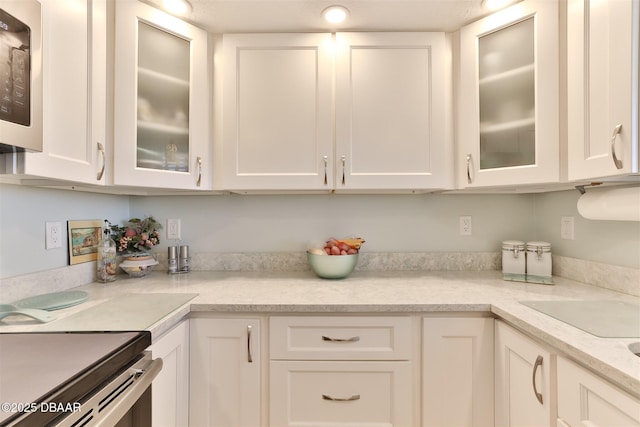 kitchen featuring stainless steel microwave, glass insert cabinets, and white cabinets