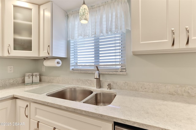 kitchen featuring glass insert cabinets, white cabinetry, light stone counters, and a sink