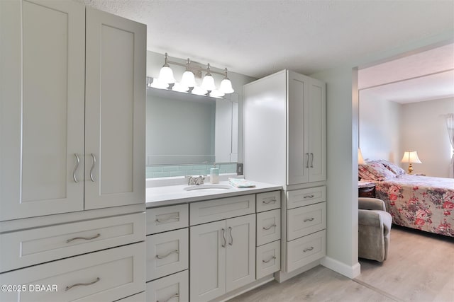 bathroom featuring ensuite bathroom, a textured ceiling, wood finished floors, vanity, and decorative backsplash