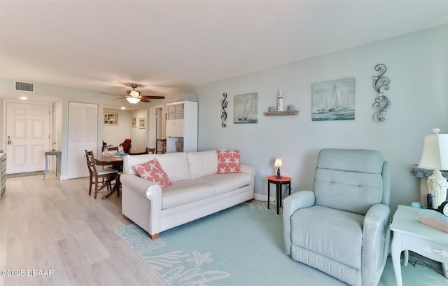 living area featuring light wood finished floors, baseboards, visible vents, and a ceiling fan