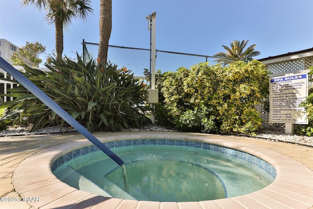 view of swimming pool featuring a hot tub and fence