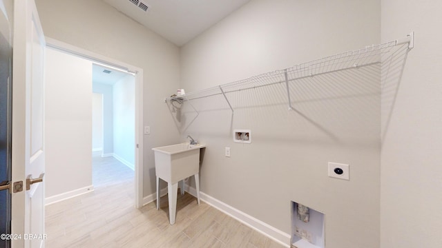 clothes washing area with hookup for an electric dryer, hookup for a washing machine, and light wood-type flooring