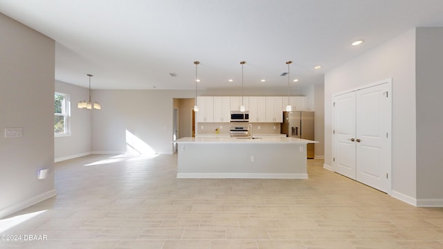 kitchen with stainless steel appliances, a chandelier, an island with sink, and pendant lighting