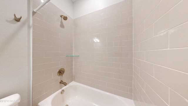 bathroom with tiled shower / bath combo and toilet