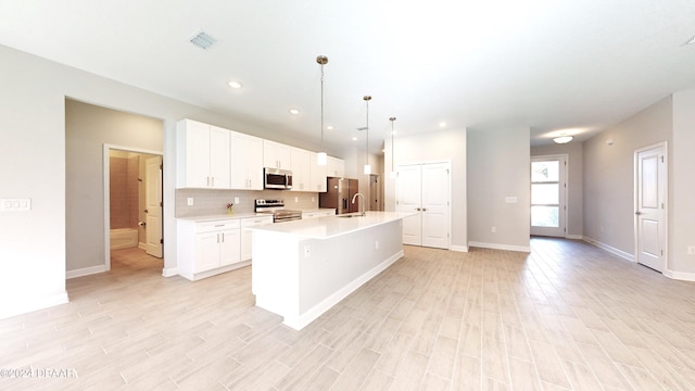 kitchen with white cabinetry, pendant lighting, an island with sink, and stainless steel appliances