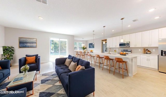 living area with visible vents, recessed lighting, light wood finished floors, and baseboards