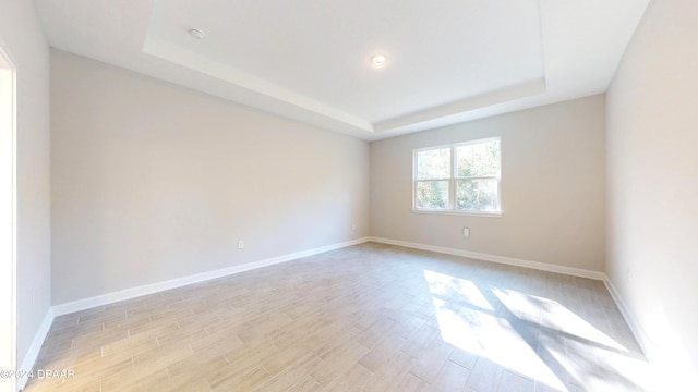 unfurnished room with a raised ceiling and light hardwood / wood-style flooring