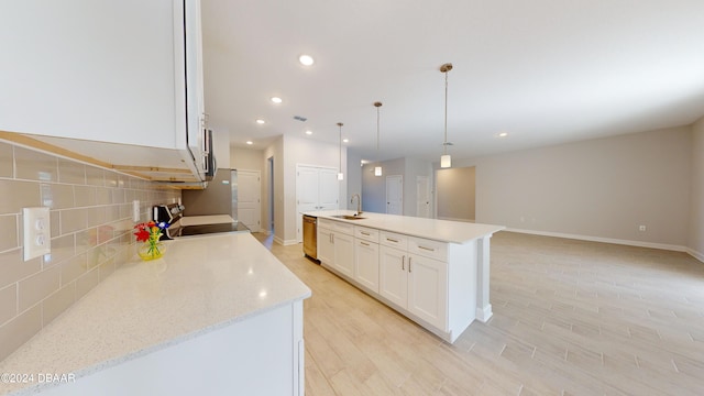 kitchen featuring white cabinetry, sink, stainless steel appliances, an island with sink, and decorative light fixtures