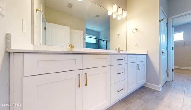 bathroom with a wealth of natural light, vanity, and walk in shower