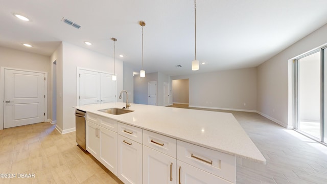 kitchen with a kitchen island with sink, hanging light fixtures, sink, light wood-type flooring, and white cabinetry