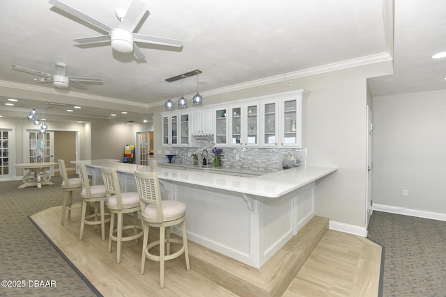3315 S Atlantic Ave Unit 1606, Daytona Beach Shores, FL 32118 - kitchen with ornamental molding, a kitchen bar, a peninsula, white cabinets, and backsplash