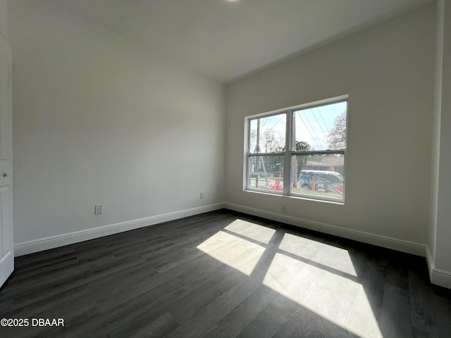 unfurnished room featuring dark wood-type flooring and baseboards