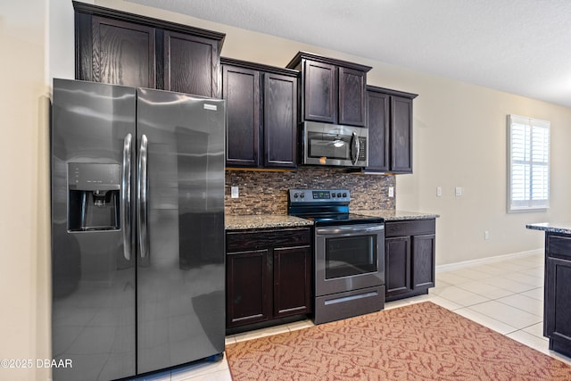 kitchen with light tile patterned floors, tasteful backsplash, appliances with stainless steel finishes, and light stone counters