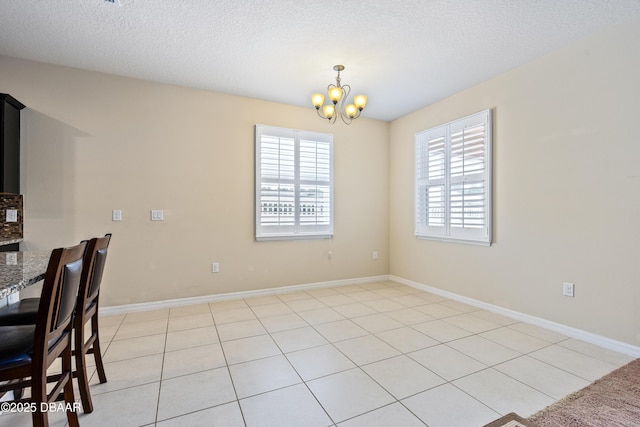 dining area with a chandelier, a textured ceiling, and baseboards