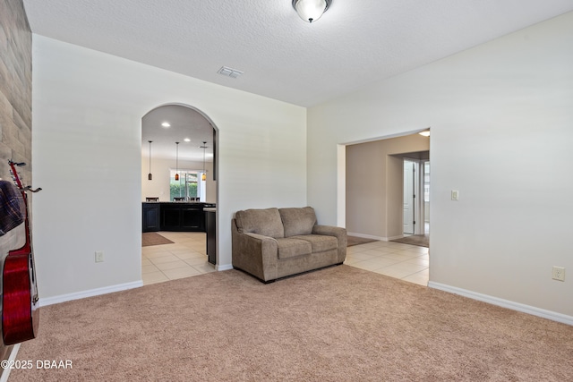 sitting room with light carpet, visible vents, arched walkways, a textured ceiling, and light tile patterned flooring