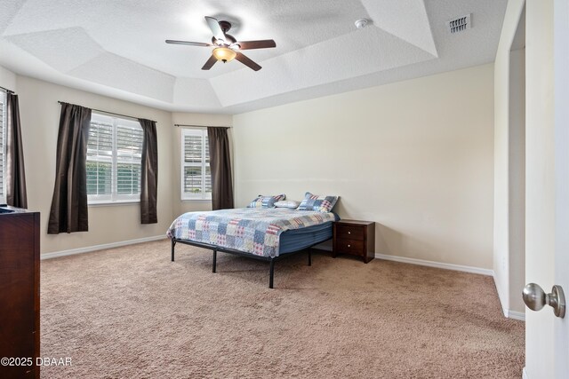 bedroom featuring a textured ceiling, carpet floors, a tray ceiling, and visible vents