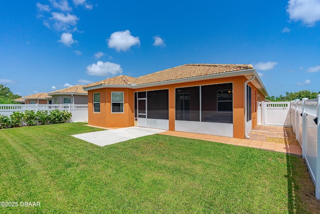 back of property with a patio, a lawn, a sunroom, a fenced backyard, and a tiled roof