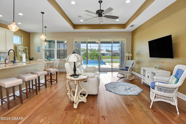 living room featuring plenty of natural light, a raised ceiling, and light hardwood / wood-style flooring