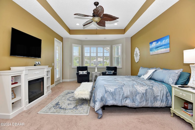 carpeted bedroom featuring ceiling fan and a raised ceiling