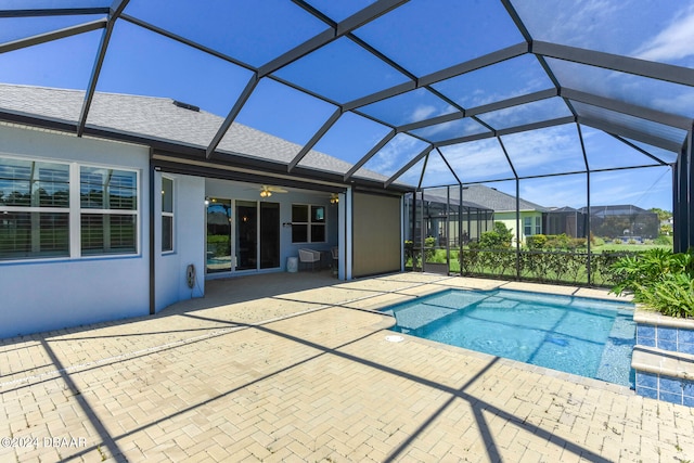 view of pool with ceiling fan, glass enclosure, and a patio area