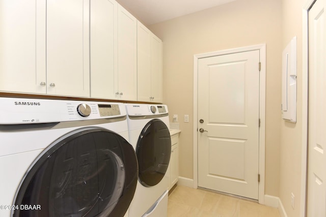 laundry area featuring cabinets, washing machine and clothes dryer, and light tile patterned floors