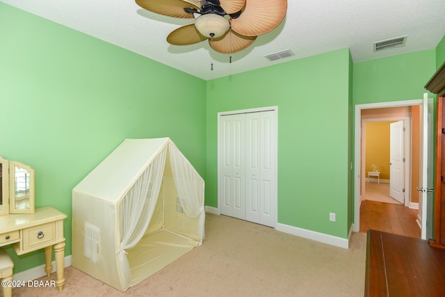 carpeted bedroom featuring a textured ceiling, ceiling fan, and a closet