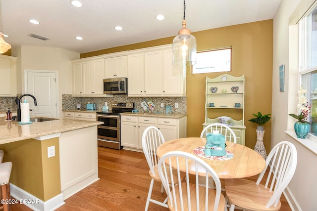 kitchen with plenty of natural light, light stone countertops, light hardwood / wood-style flooring, and stainless steel appliances