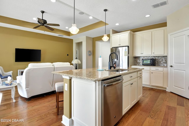 kitchen with hardwood / wood-style floors, sink, a kitchen island with sink, and appliances with stainless steel finishes