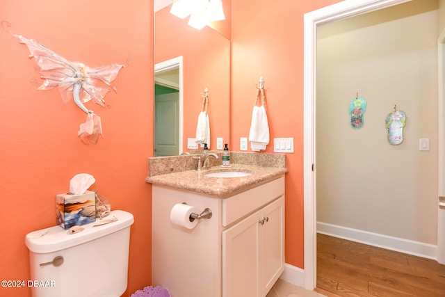 bathroom featuring toilet, vanity, hardwood / wood-style floors, and ceiling fan