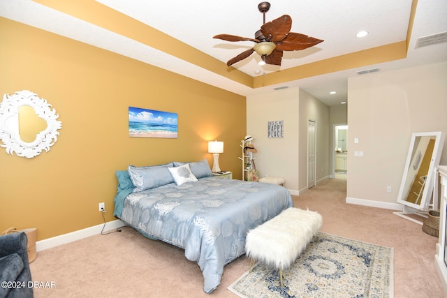 bedroom featuring light carpet, ceiling fan, and a raised ceiling